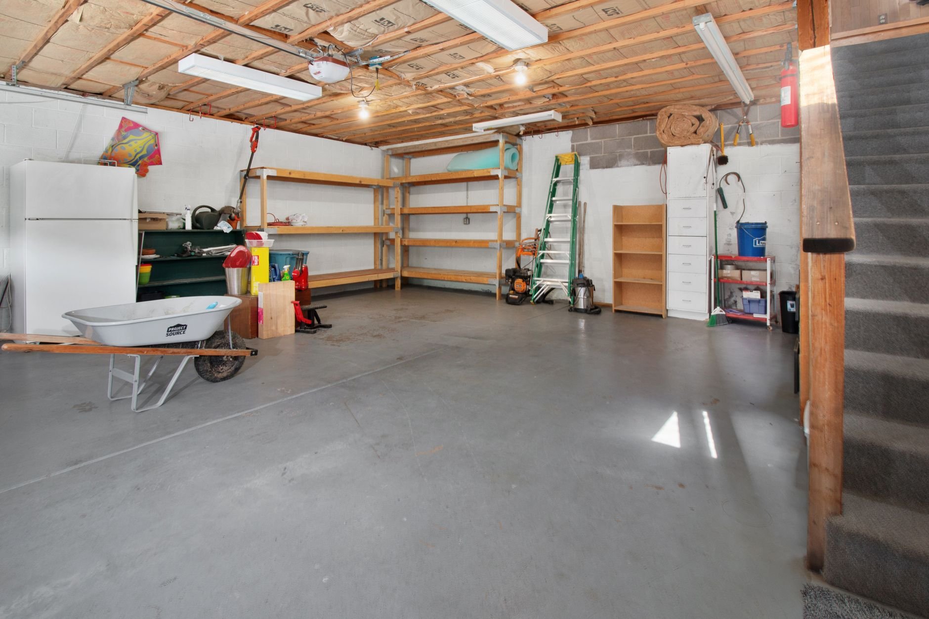 Spacious garage interior with storage shelves and tools — all the things neighbours already own.